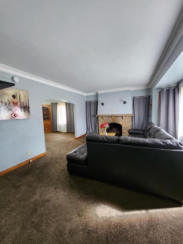 living area featuring arched walkways, a stone fireplace, carpet, baseboards, and ornamental molding