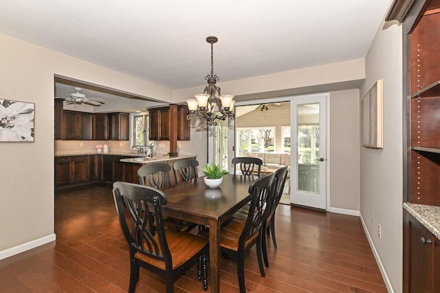 dining room featuring baseboards, plenty of natural light, ceiling fan with notable chandelier, and dark wood-style floors