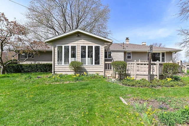 back of property with a yard, a chimney, and a wooden deck