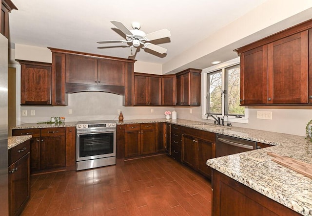 kitchen featuring light stone countertops, a sink, stainless steel appliances, a ceiling fan, and dark wood-type flooring