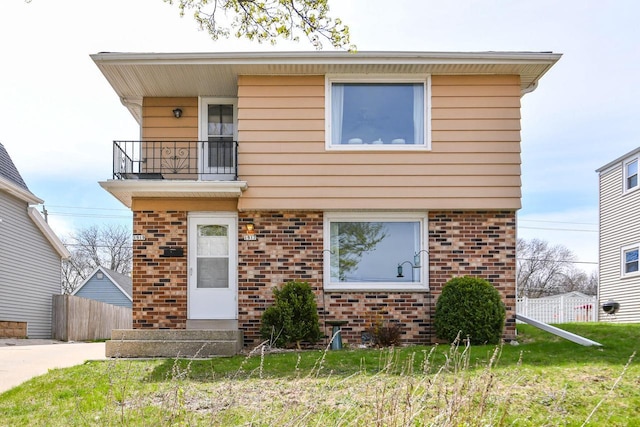 view of front of home with fence, brick siding, and a balcony