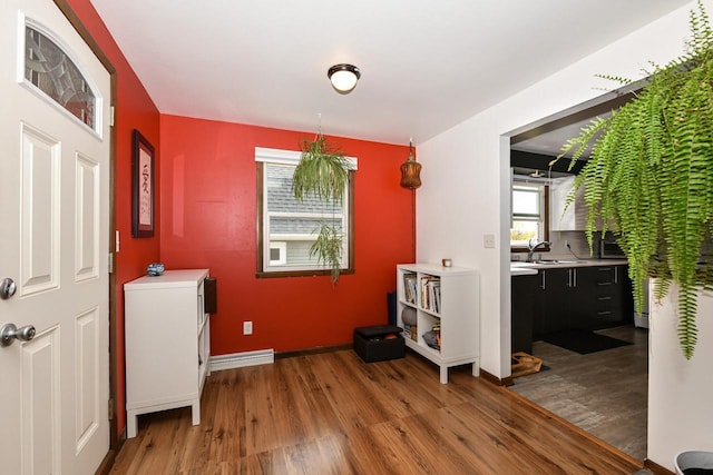 laundry room with baseboards, a sink, and wood finished floors