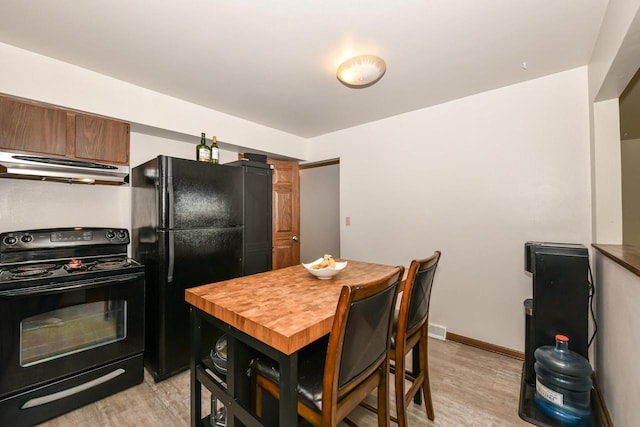 kitchen with butcher block counters, baseboards, light wood-type flooring, under cabinet range hood, and black appliances