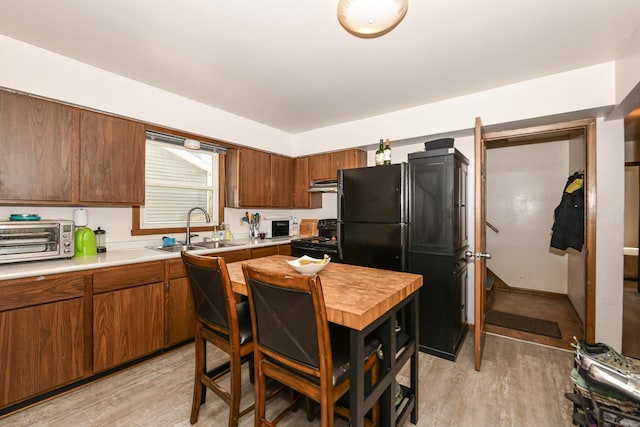 kitchen with a toaster, light wood-style floors, light countertops, a sink, and black appliances