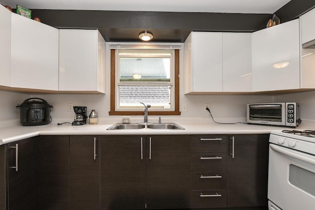 kitchen featuring white cabinets, gas range gas stove, a sink, and a toaster