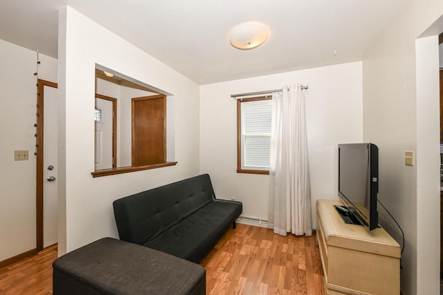 living area featuring a baseboard heating unit and light wood finished floors
