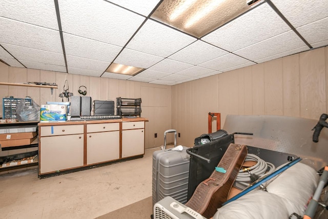 basement featuring a drop ceiling and a decorative wall
