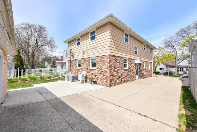 view of home's exterior featuring brick siding, a patio area, and fence