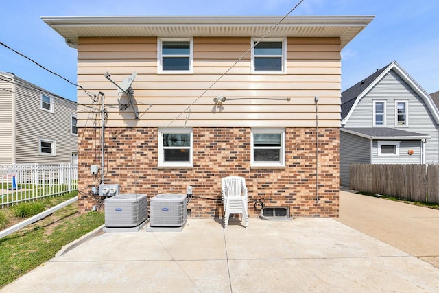 back of property with fence, a patio, cooling unit, and brick siding