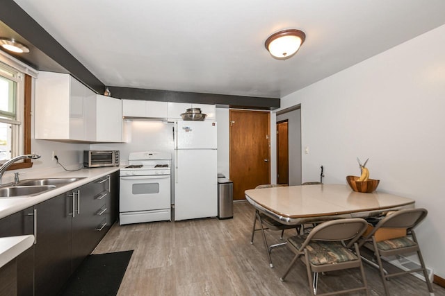 kitchen with a sink, light wood-style floors, white appliances, light countertops, and a toaster