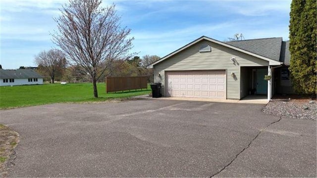 view of property exterior featuring an attached garage, a yard, and aphalt driveway