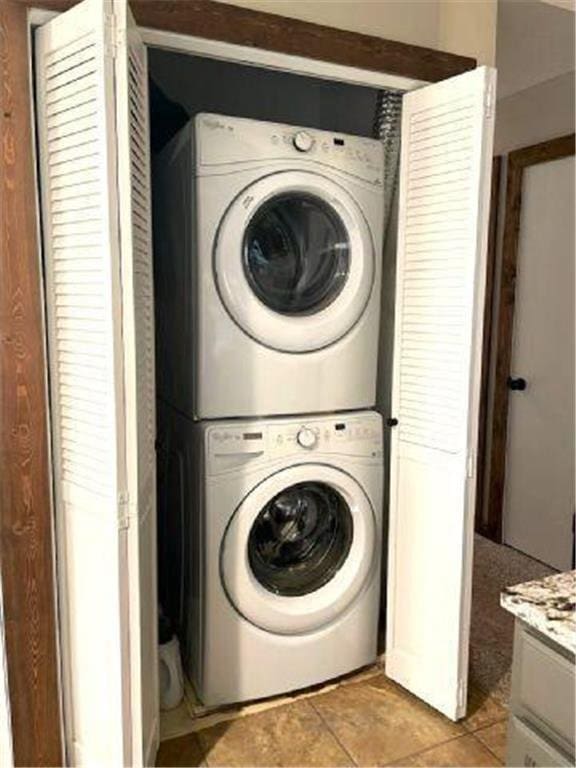 laundry room with laundry area, light tile patterned floors, and stacked washer / dryer