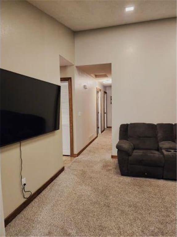 living area with baseboards and light colored carpet