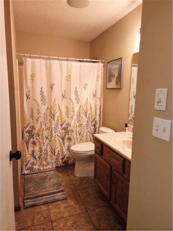 full bath featuring vanity, toilet, tile patterned floors, a textured ceiling, and curtained shower