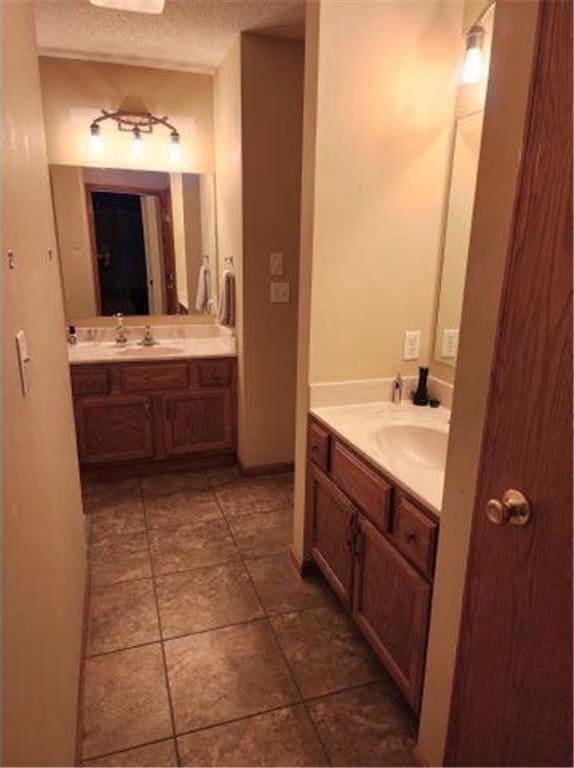 bathroom featuring tile patterned flooring, a sink, and two vanities