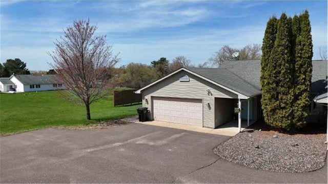 view of side of home with a yard, a garage, and aphalt driveway