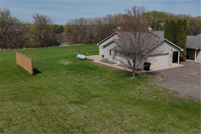 view of property exterior with an attached garage, a yard, and driveway