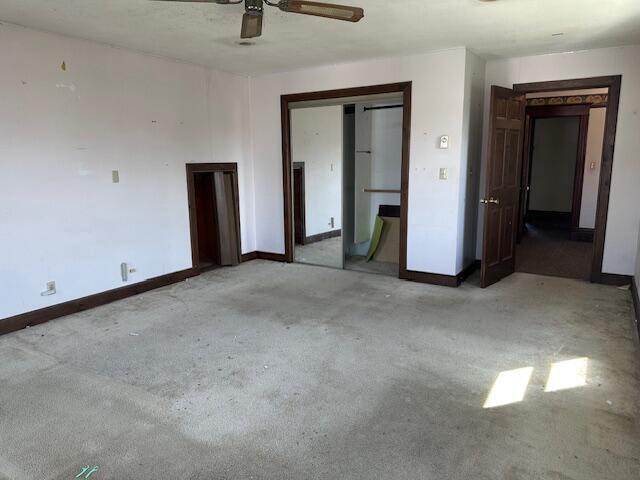 unfurnished bedroom featuring a closet, carpet floors, baseboards, and a ceiling fan