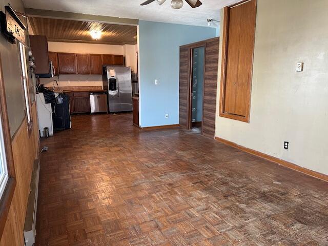 kitchen with dark countertops, appliances with stainless steel finishes, baseboards, and ceiling fan