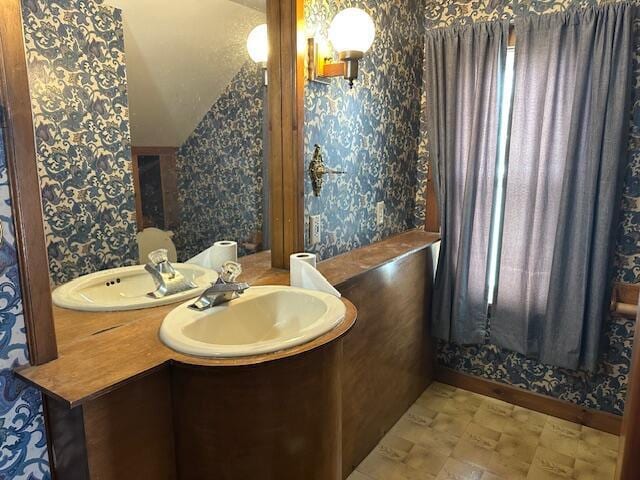 bathroom with vanity, baseboards, and wallpapered walls
