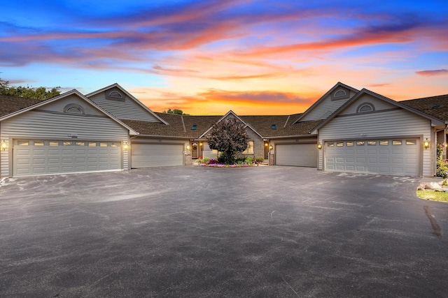single story home featuring roof with shingles, an attached garage, and aphalt driveway