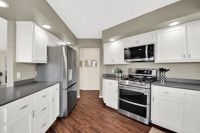 kitchen featuring dark countertops, stainless steel appliances, dark wood finished floors, and white cabinetry