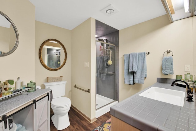 bathroom featuring vanity, toilet, wood finished floors, and a stall shower