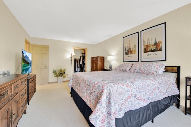 bedroom featuring a closet, baseboards, a spacious closet, and light carpet