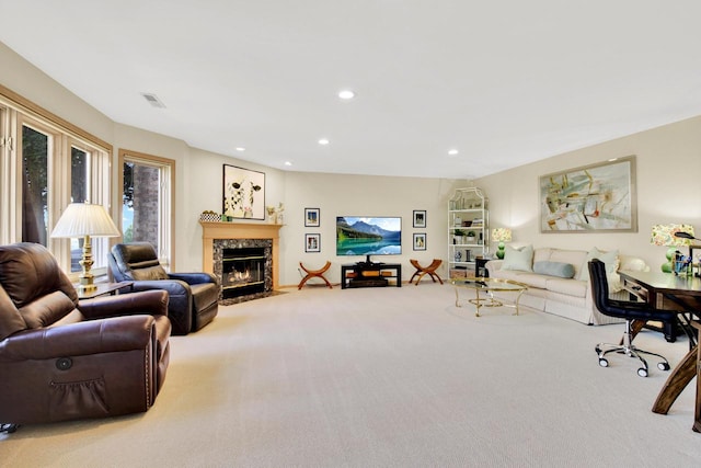 carpeted living room with a high end fireplace, recessed lighting, and visible vents