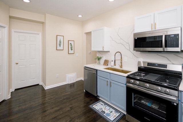 kitchen with appliances with stainless steel finishes, a sink, recessed lighting, white cabinetry, and dark wood-type flooring