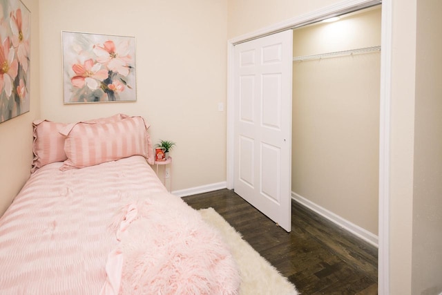 bedroom featuring baseboards, dark wood finished floors, and a closet