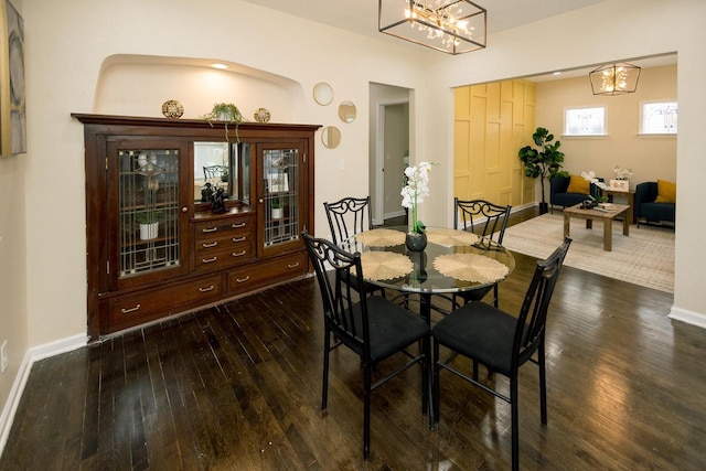 dining area featuring baseboards, a chandelier, and dark wood-type flooring