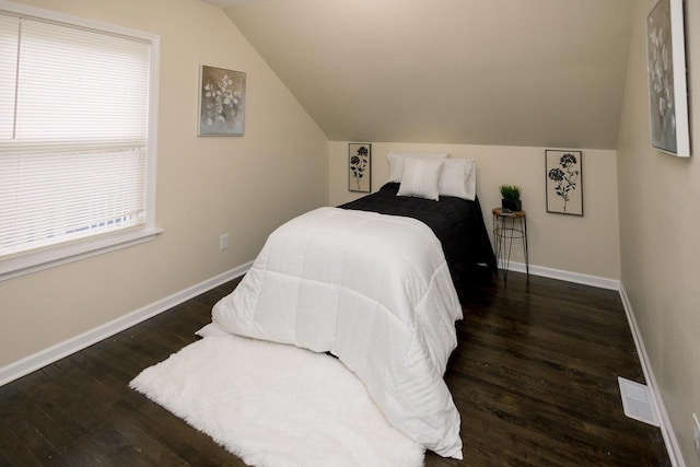 bedroom with baseboards, lofted ceiling, wood finished floors, and visible vents