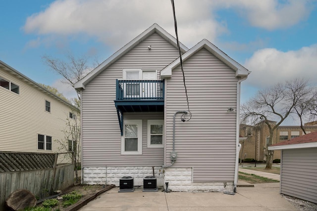 rear view of house featuring fence, central AC unit, and a balcony