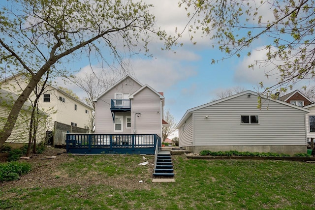 back of house featuring a lawn, stairway, a balcony, and a deck