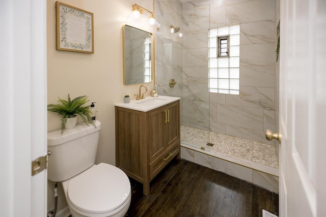 full bath featuring vanity, wood-type flooring, toilet, and tiled shower