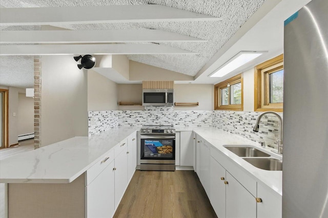 kitchen with appliances with stainless steel finishes, open shelves, a sink, a peninsula, and light wood finished floors