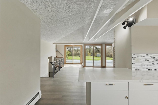 kitchen with decorative backsplash, a textured ceiling, vaulted ceiling, wood finished floors, and light countertops