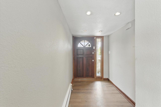 entrance foyer with a textured wall, baseboards, light wood-style floors, recessed lighting, and a baseboard heating unit