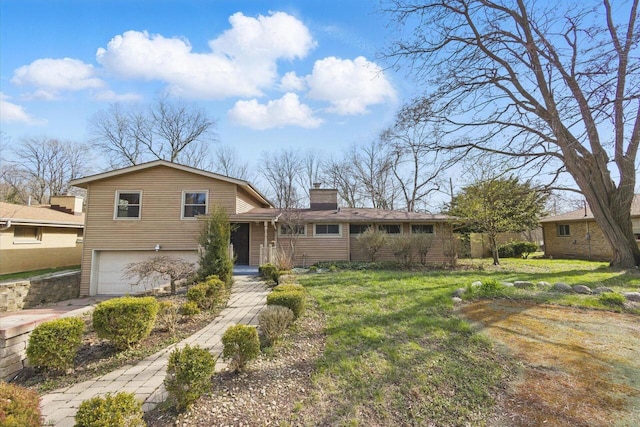 tri-level home with an attached garage, a chimney, and a front yard
