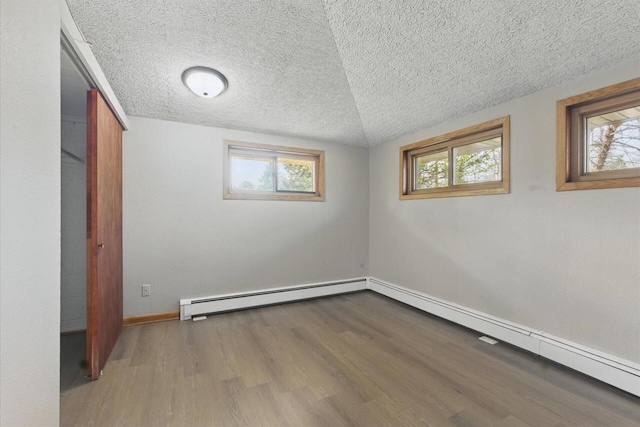 interior space featuring a baseboard radiator, a textured ceiling, wood finished floors, and multiple windows