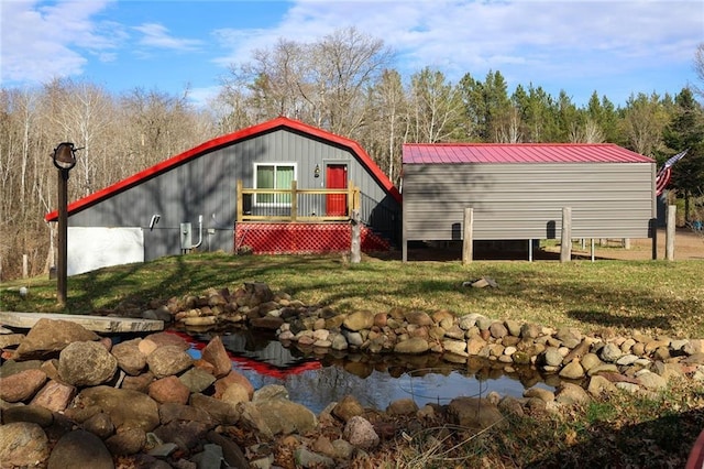 N8690 Island Lake Rd, Spooner, WI 54801 - back of house with a yard, metal roof, and a small pond