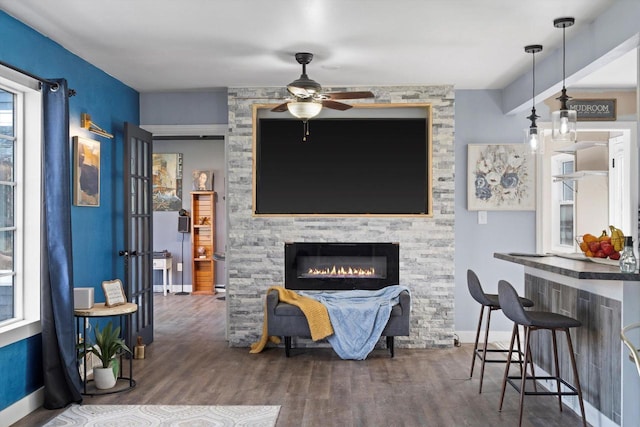 living room with baseboards, ceiling fan, and wood finished floors