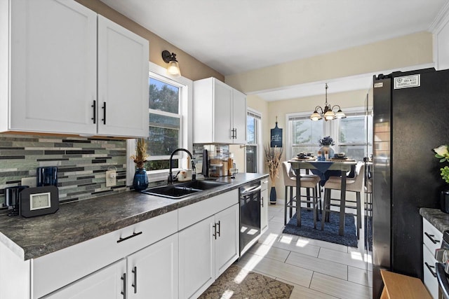 kitchen featuring freestanding refrigerator, backsplash, a sink, and dishwasher