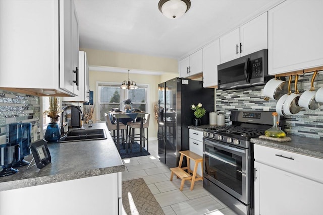 kitchen featuring white cabinets, appliances with stainless steel finishes, an inviting chandelier, a sink, and decorative backsplash