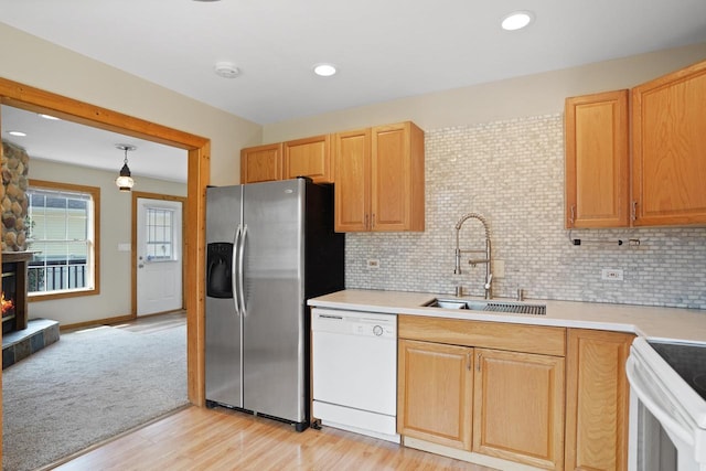 kitchen with a sink, light countertops, decorative backsplash, and white appliances