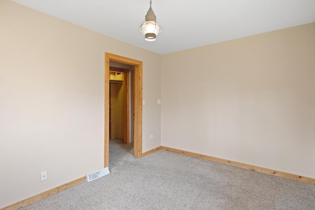 empty room with baseboards, light colored carpet, and visible vents