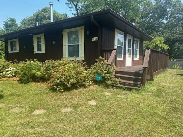 view of front of property featuring a front lawn and a wooden deck