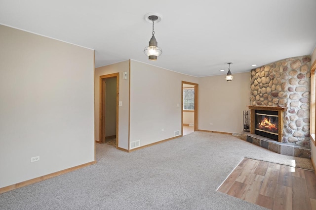 unfurnished living room featuring baseboards, a fireplace, and carpet flooring