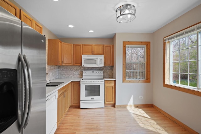 kitchen featuring light countertops, light wood-type flooring, white appliances, and a wealth of natural light